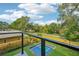 View from the balcony of a private yard with a pool and landscaping on a sunny day with blue skies and white clouds at 1630 Douglas Ave, Dunedin, FL 34698