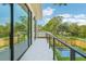 View from the balcony of a private yard with a pool and landscaping on a sunny day with blue skies and white clouds at 1630 Douglas Ave, Dunedin, FL 34698