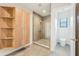 Spacious bathroom showcases a glass-enclosed shower, wood shelving, and a toilet at 1630 Douglas Ave, Dunedin, FL 34698