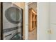 Close-up of laundry with modern stackable washer and dryer and built-in wood shelving at 1630 Douglas Ave, Dunedin, FL 34698