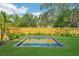 Backyard featuring a pool, wood fence, lush lawn, and manicured greenery at 1630 Douglas Ave, Dunedin, FL 34698