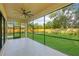 Screened porch with fan overlooking the green backyard with a fence and a swimming pool at 1630 Douglas Ave, Dunedin, FL 34698