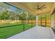 Relaxing screened porch with tile flooring overlooking the large backyard with lush lawn and privacy fence at 1630 Douglas Ave, Dunedin, FL 34698