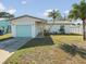Charming home with a bright, colorful garage door, palm trees, and inviting curb appeal at 15810 2Nd E St, Redington Beach, FL 33708