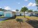 Charming single-story home featuring a blue garage door, light exterior paint, and a well-manicured lawn at 15810 2Nd E St, Redington Beach, FL 33708