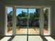 Covered wooden patio area and green outdoor space viewed through sliding glass doors at 15810 2Nd E St, Redington Beach, FL 33708