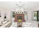 Cozy living room showcasing a brick fireplace, large windows, and access to the outdoor pool area at 4787 Hamlets Grove Dr, Sarasota, FL 34235