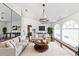 Spacious living room with hardwood floors, a modern chandelier, and bright, arched windows at 4787 Hamlets Grove Dr, Sarasota, FL 34235