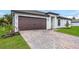 Brown double-door garage with a brick paved driveway and lush landscaping at 5952 Gillot Blvd, Port Charlotte, FL 33981