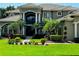 Elegant home featuring a tile roof, well-manicured lawn, and lush tropical landscaping with palm trees at 5016 Givendale Ln, Tampa, FL 33647