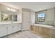 Bright bathroom featuring soaking tub, neutral tile surround, and dual sink vanity at 3767 Dragonfly Trl, Odessa, FL 33556