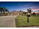 Three-car garage home with lush landscaping at dusk at 10301 Manta Way, Tampa, FL 33615