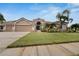 Tan house with three car garage, manicured lawn, and palm trees at 10301 Manta Way, Tampa, FL 33615