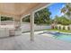 Outdoor kitchen and pool deck with built-in grill, sink, refrigerator, and tiled pool with integrated jacuzzi at 4005 W San Rafael St, Tampa, FL 33629