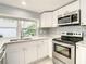 Modern kitchen with white cabinets, granite counters, and stainless steel appliances at 3604 Rockaway Dr, Holiday, FL 34691