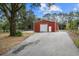 Red metal barn with a large roll-up door and spacious paved area at 11623 Innfields Dr, Odessa, FL 33556