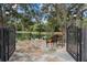 Stone patio with seating area, iron gates, and a picturesque view of a private pond at 11623 Innfields Dr, Odessa, FL 33556