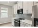 Modern kitchen with white cabinets, gray backsplash, and stainless steel appliances at 11223 Livewell Ct, Venice, FL 34293