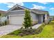 Exterior view of a single-story home with a gray exterior, white garage door and landscaping at 11223 Livewell Ct, Venice, FL 34293