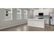 Open concept kitchen with white cabinets, gray backsplash, and kitchen island at 11223 Livewell Ct, Venice, FL 34293