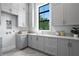 Bright laundry room featuring shaker cabinets, quartz countertops, and a window for ample natural light at 5032 W Longfellow Ave, Tampa, FL 33629