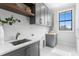 Laundry room featuring gray cabinets, sleek countertops, and wooden shelving accents at 5032 W Longfellow Ave, Tampa, FL 33629