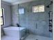 Contemporary bathroom featuring a glass-enclosed shower, a soaking tub, and stylish gray tiling at 3109 W Knights Ave, Tampa, FL 33611