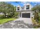Stunning two-story home featuring a modern design, lush landscaping, and a gray brick driveway at 3109 W Knights Ave, Tampa, FL 33611
