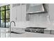 Modern kitchen with stainless steel range hood, marble backsplash, and window view at 3109 W Knights Ave, Tampa, FL 33611