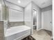 Inviting bathroom featuring a soaking tub with tile surround, window, and separate toilet room at 11946 Brighton Knoll Loop, Riverview, FL 33579