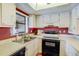 Galley kitchen with white cabinets and black appliances at 2400 Winding Creek Blvd # 3-202, Clearwater, FL 33761