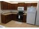 Kitchen with brown cabinets, gas range, microwave, and white refrigerator at 10319 Avelar Ridge Dr, Riverview, FL 33578