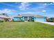 Inviting single-story home featuring a beautiful turquoise exterior, landscaped front yard, and an attached two-car garage at 555 Rotonda Cir, Rotonda West, FL 33947