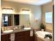 Well-lit bathroom featuring dual sinks, wooden cabinets, a soaking tub, and a decorative mirror at 8529 Kenton Rd, Wesley Chapel, FL 33545