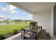 Covered patio with stylish dining set overlooking a serene lake and green lawn at 17721 Roost Pl, Lakewood Ranch, FL 34211