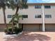 Three-story townhome featuring an attached garage, brick driveway, and tropical landscaping at 12246 2Nd E St # 503, Treasure Island, FL 33706