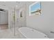 Bright bathroom featuring a soaking tub, glass shower, and marble-style tile at 2355 Bahia Vista St, Sarasota, FL 34239