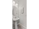 Simple half bathroom features a pedestal sink, wall mirror, and decorative wall art at 9658 Sweetwell Pl, Riverview, FL 33569