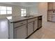 Kitchen island features granite countertop, stainless dishwasher, and gray cabinets at 2855 Maiden Grass Isle, Wesley Chapel, FL 33543