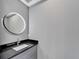 Bathroom features a sleek, granite-topped vanity with LED lighted circular mirror and modern faucet at 534 Estuary Shore Ln, Apollo Beach, FL 33572