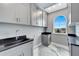 Well-lit laundry room with gray cabinets and black countertop with a gray epoxy floor and a window view at 534 Estuary Shore Ln, Apollo Beach, FL 33572