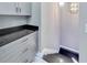 Gray laundry room with modern cabinets, black countertops, recessed lights, and epoxy floor at 534 Estuary Shore Ln, Apollo Beach, FL 33572