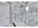 Walk-in shower with marble-look tile, dual shower heads, glass surround, and white door at 534 Estuary Shore Ln, Apollo Beach, FL 33572