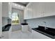 Laundry room with white cabinets, black countertop and arched window at 548 Estuary Shore Ln, Apollo Beach, FL 33572
