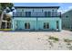 Home showcasing a backyard with white gravel, a full-length balcony, and sliding glass doors on the ground level at 3171 Sea Grape Dr, Hernando Beach, FL 34607