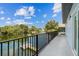 Large balcony overlooking tranquil waterfront with lush greenery, black metal railings, and blue siding at 3351 Fernleaf Dr, Hernando Beach, FL 34607