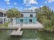 Waterfront two-story home with a private dock, light blue and white color scheme, and balconies at 3351 Fernleaf Dr, Hernando Beach, FL 34607