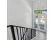 Modern staircase leading to a bright entryway with white walls, black railings, and glass doors at 3380 Holly Springs Dr, Hernando Beach, FL 34607