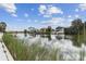 Beautiful waterfront homes reflecting in the calm water with lush vegetation in the foreground at 3380 Holly Springs Dr, Hernando Beach, FL 34607