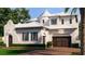 Elegant two-story home with dark wood garage doors, white exterior, and blue shuttered windows at 5009 W Spring Lake Dr, Tampa, FL 33629